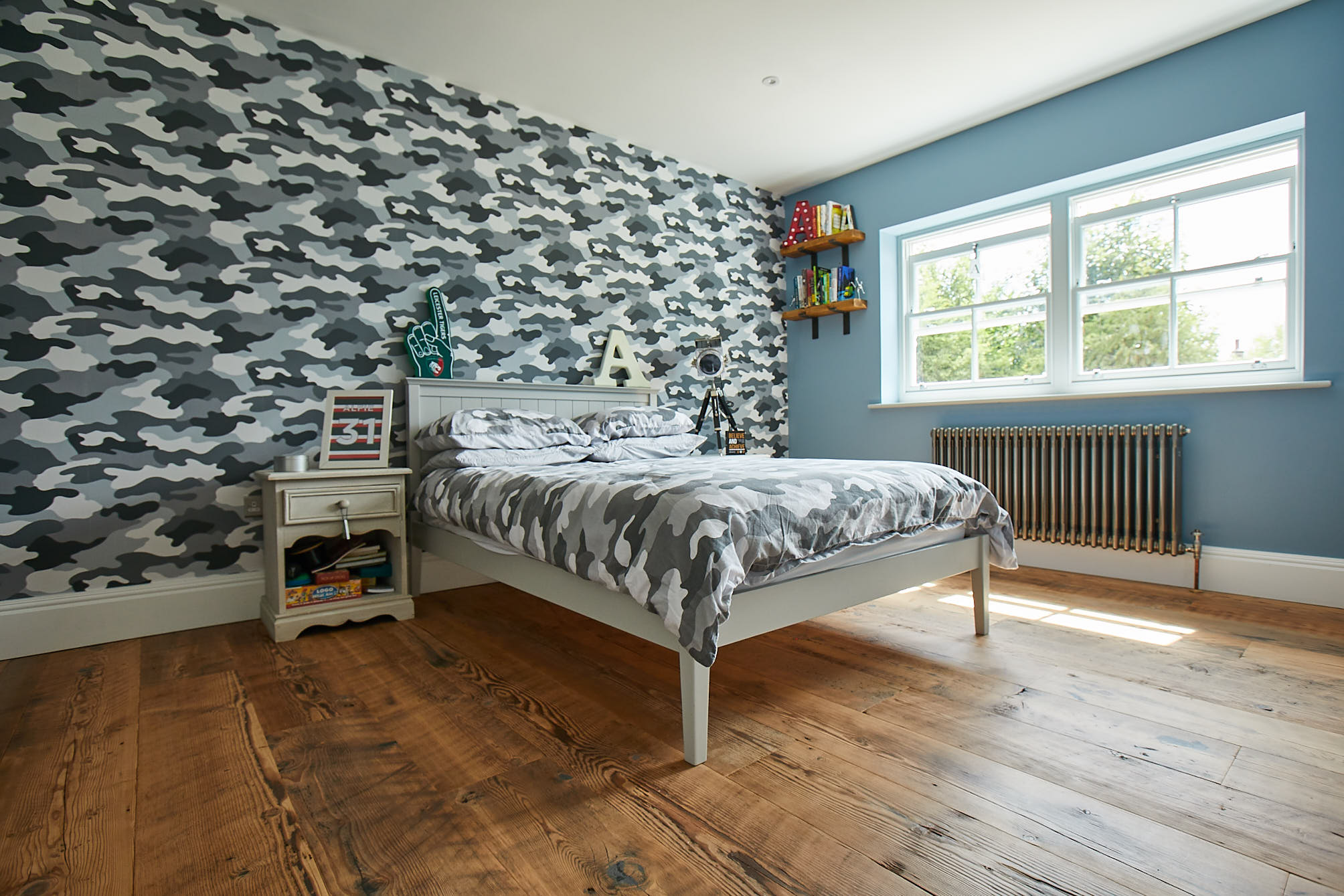 Camouflage wallpaper and rustic flooring in boys bedroom