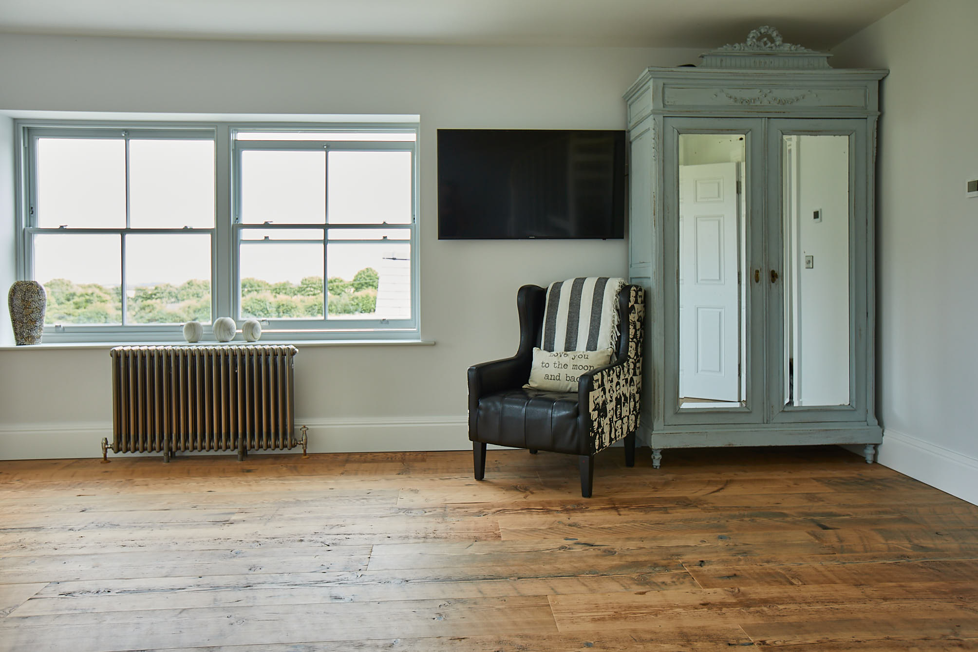 Blue wardrobe with mirrors next to black leather chair in bedroom