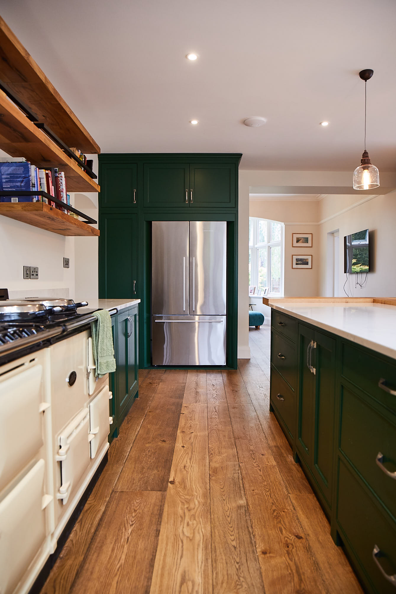 Stainless steel Fisher Paykel frindge freezer with green painted kitchen cabinets and oak flooring