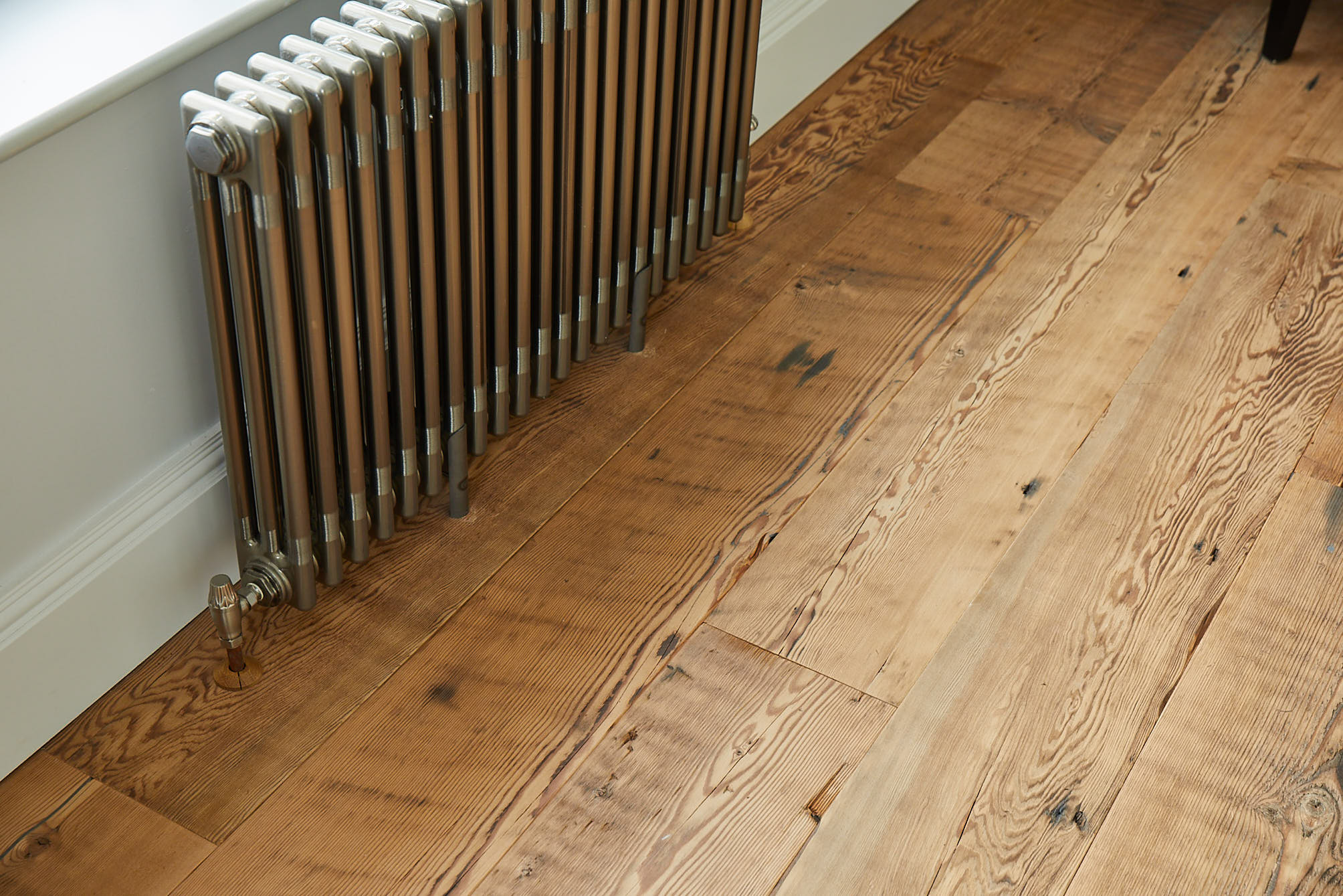 Cast iron radiator sits on reclaimed flooring