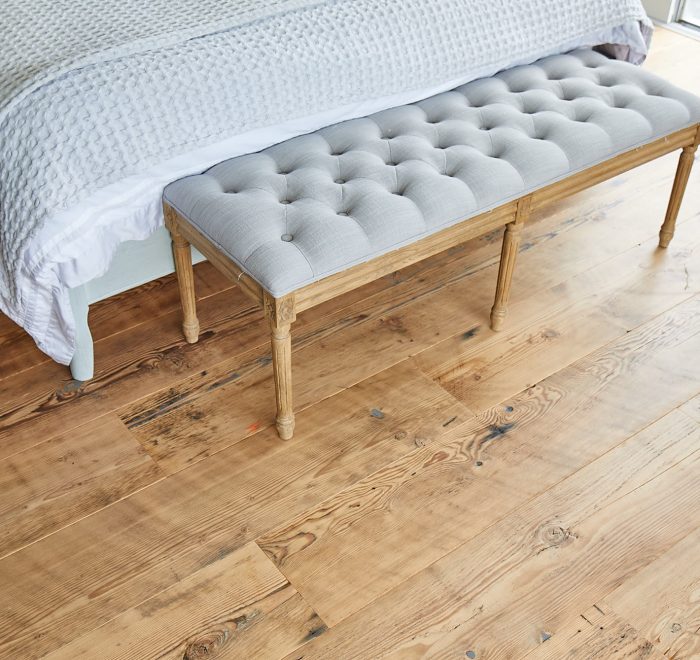 Upholstered seat on reclaimed rustic flooring by The Main Company