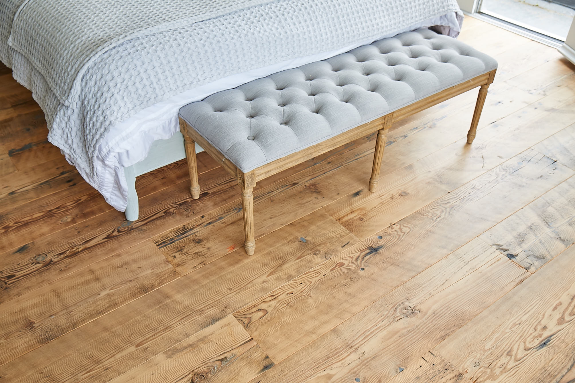 Upholstered seat on reclaimed rustic flooring by The Main Company