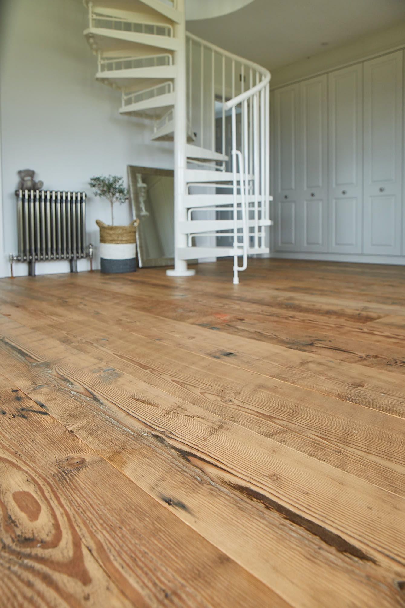 Reclaimed flooring leads to white spiral staircase