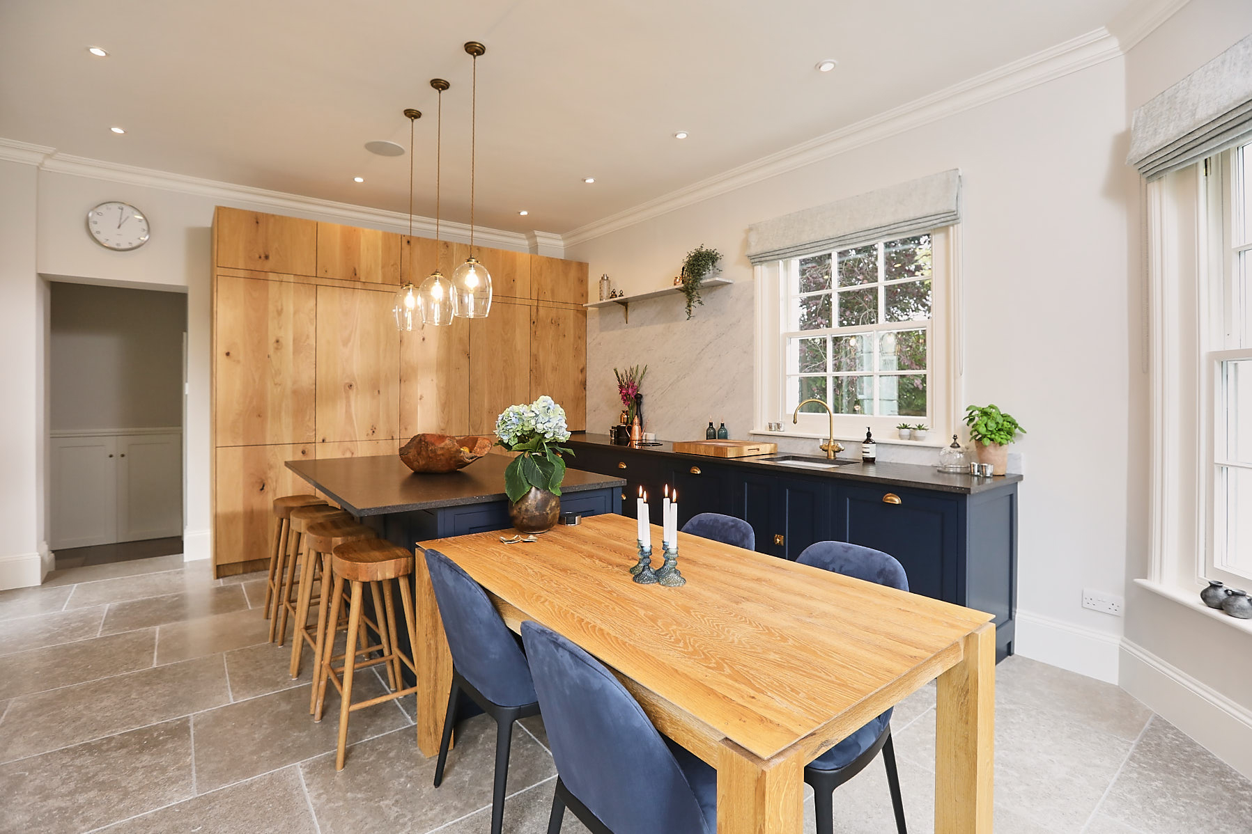 Bespoke blue kitchen with tall French oak cabinets and oak dining table