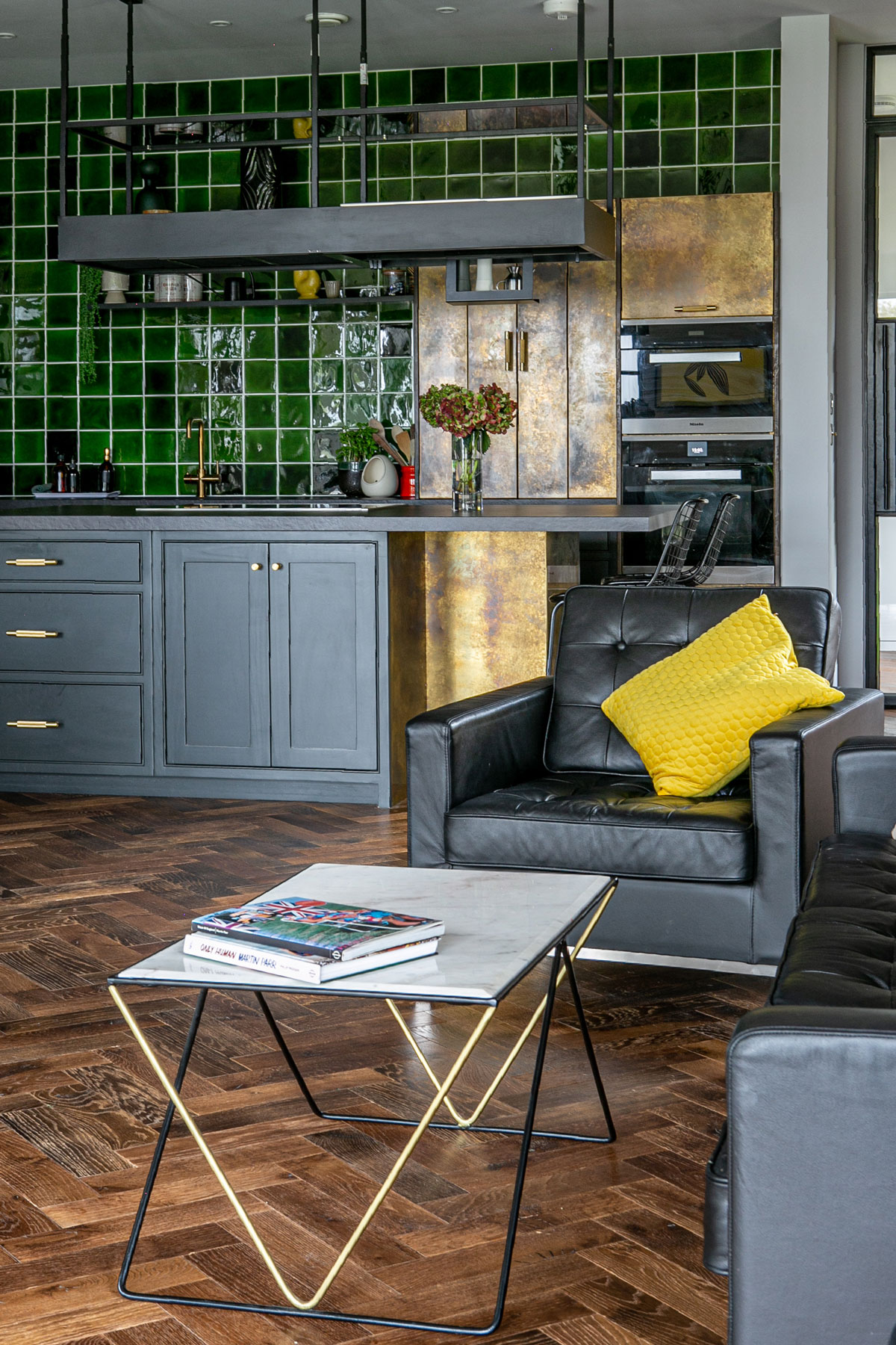 Black armchair and coffee table in open plan kitchen with parquet flooring