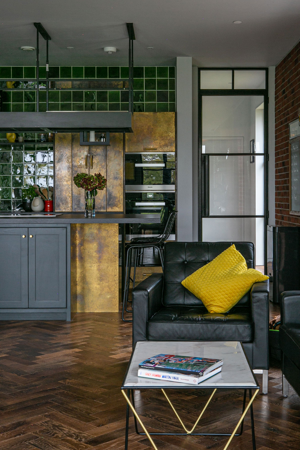 Lamp black and brass kitchen units on parquet wood floor