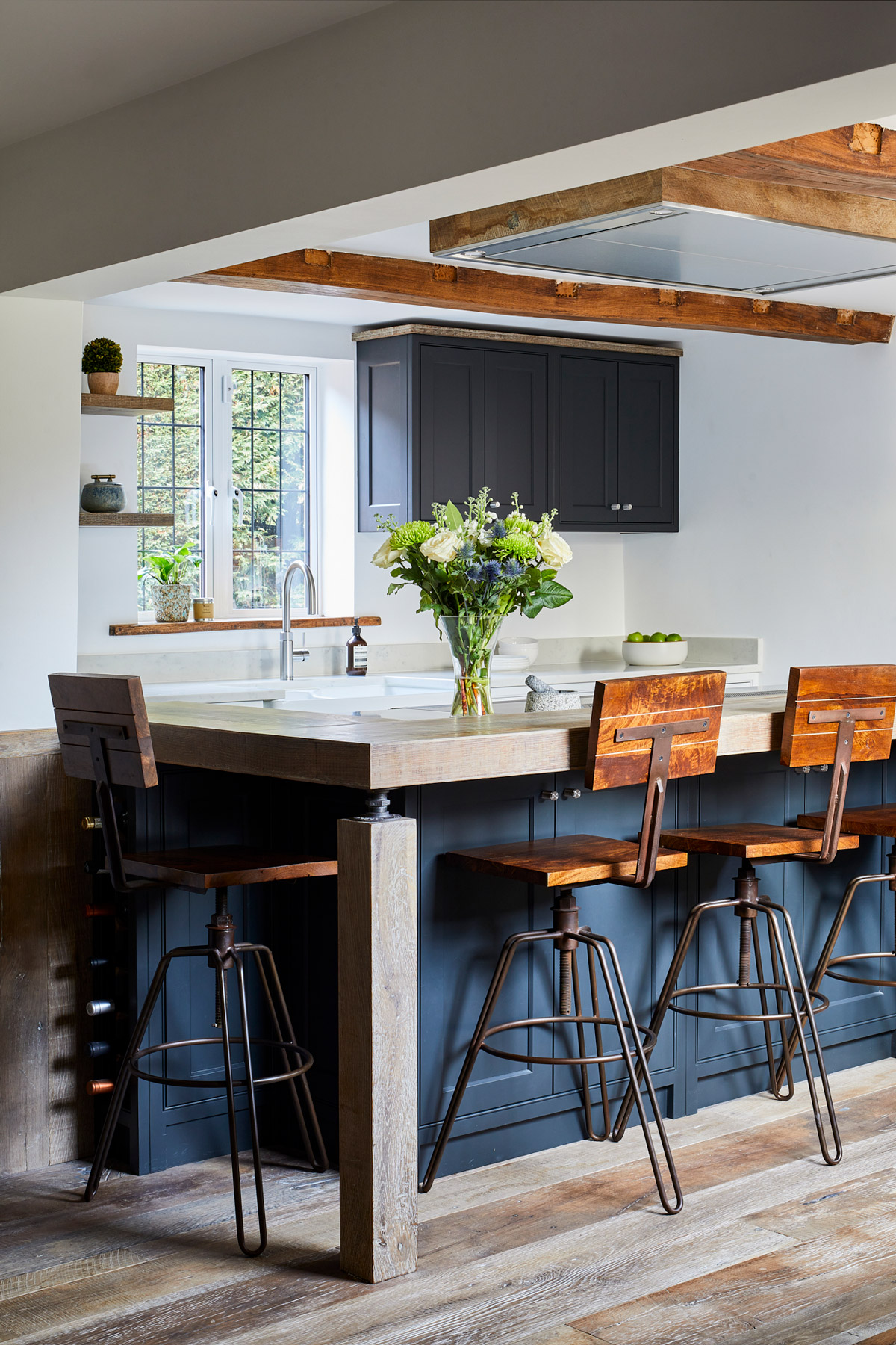 Industrial bar stools under dark kitchen island with reclaimed oak worktop