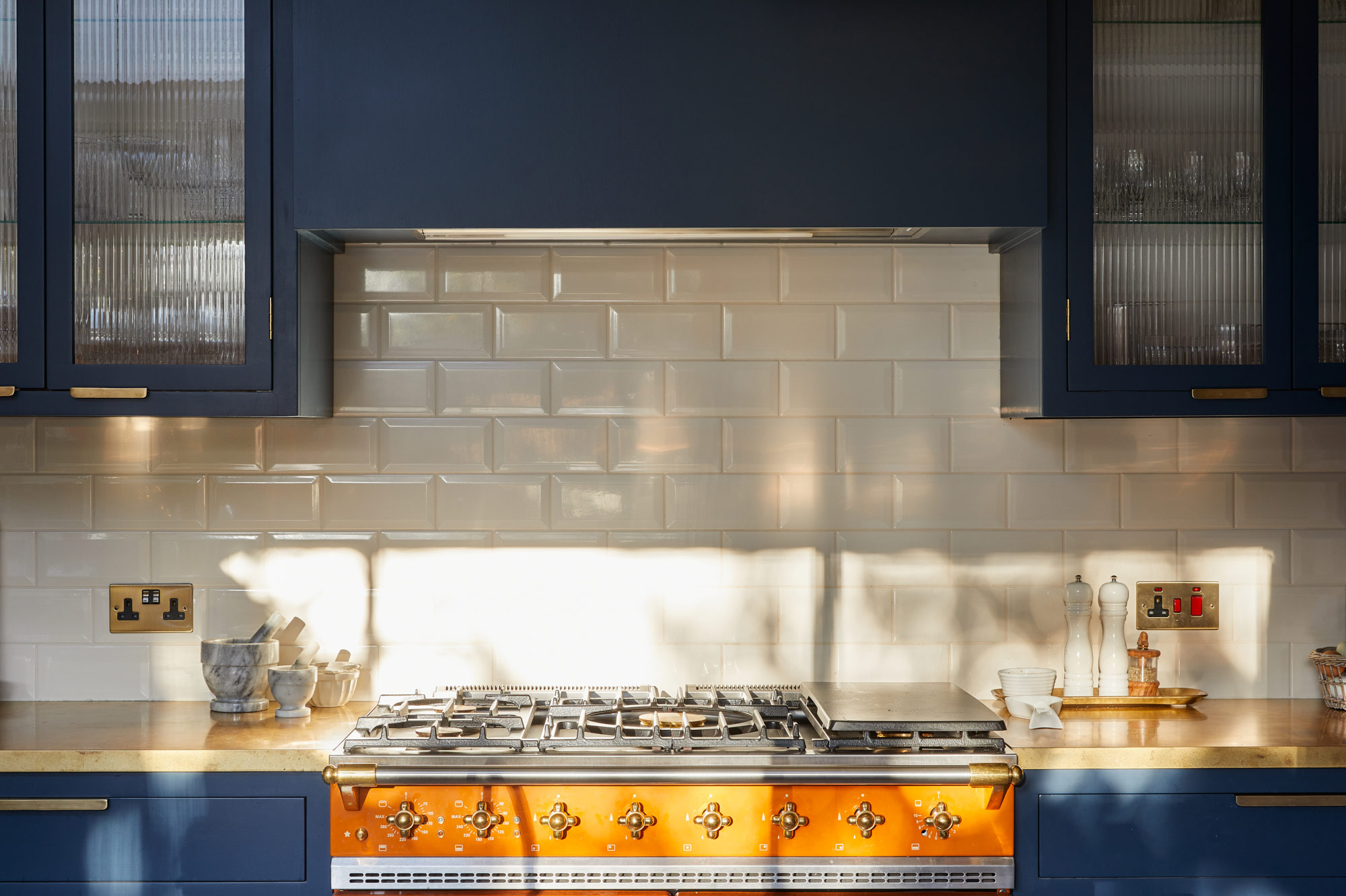 Metro tiles sit behind bright orange Lacanche cooker