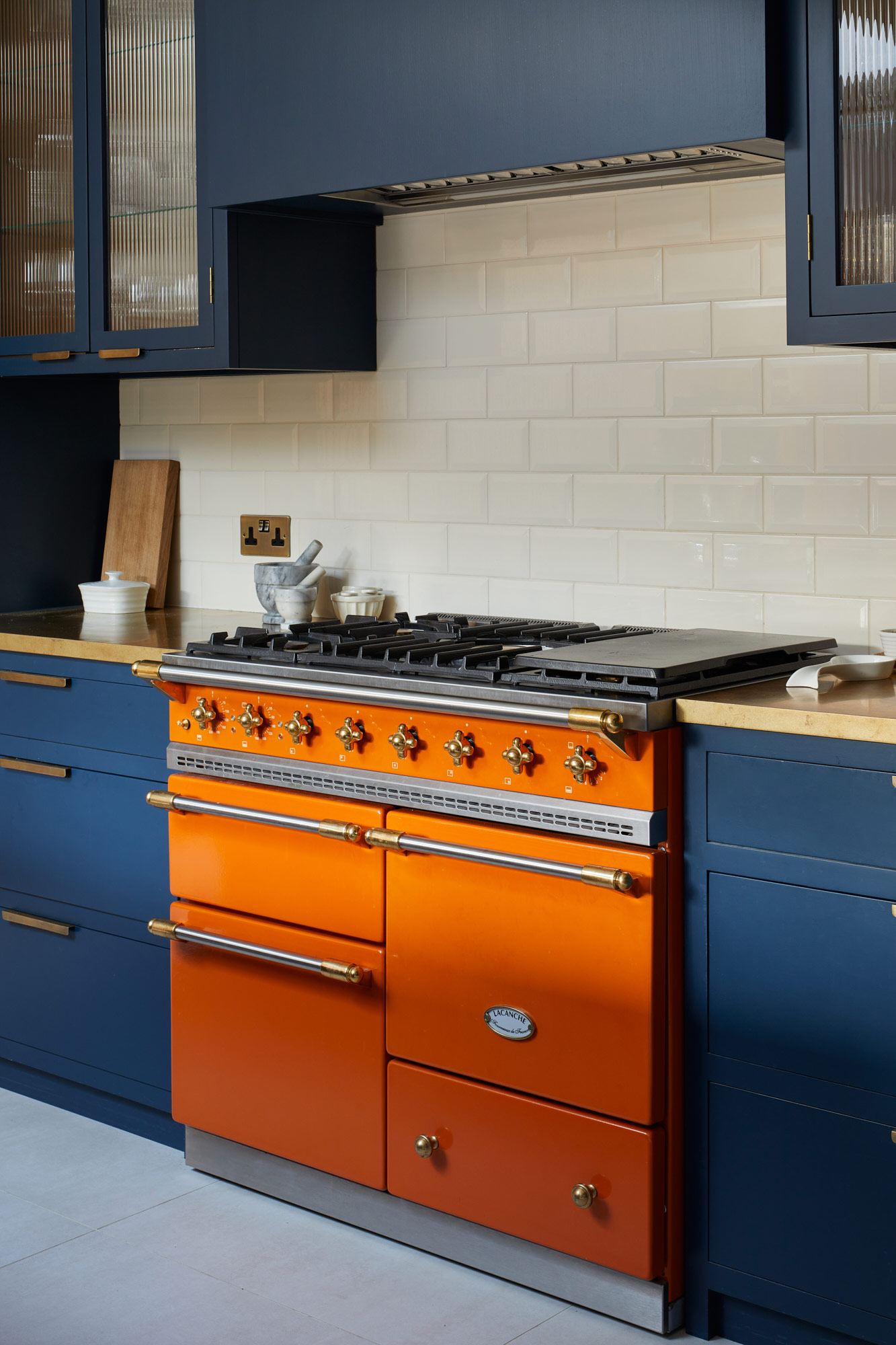 Bright orange Lacanche range cooker in bespoke kitchen by The Main Company