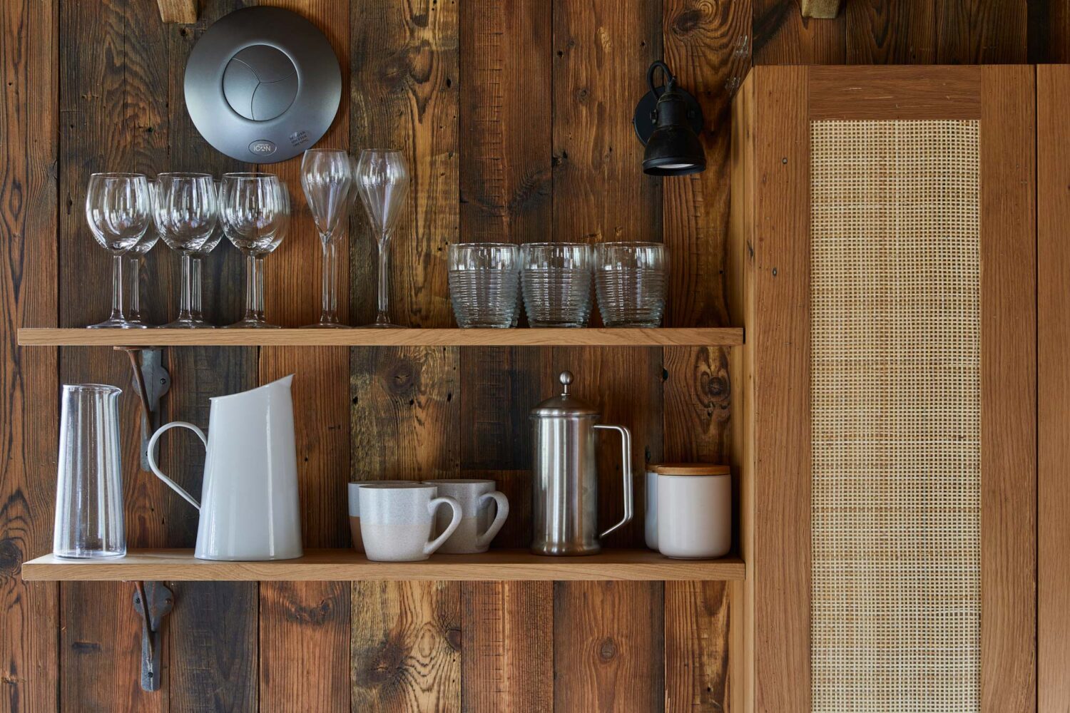 kitchen floating shelves with wood cladding in the back with rattan cupboards