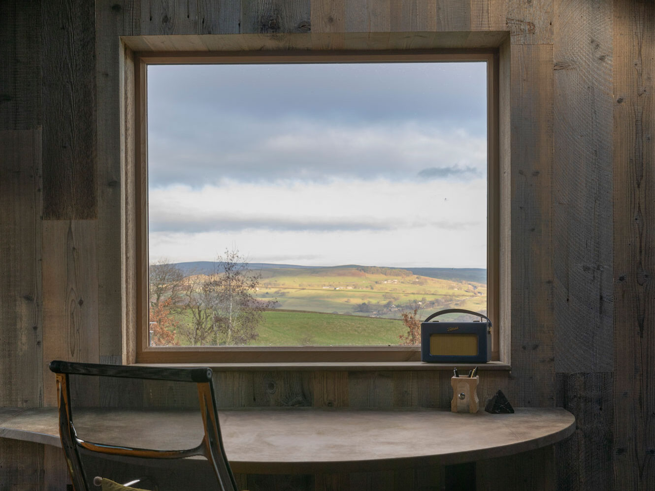 window over looking a field framed in wood cladding