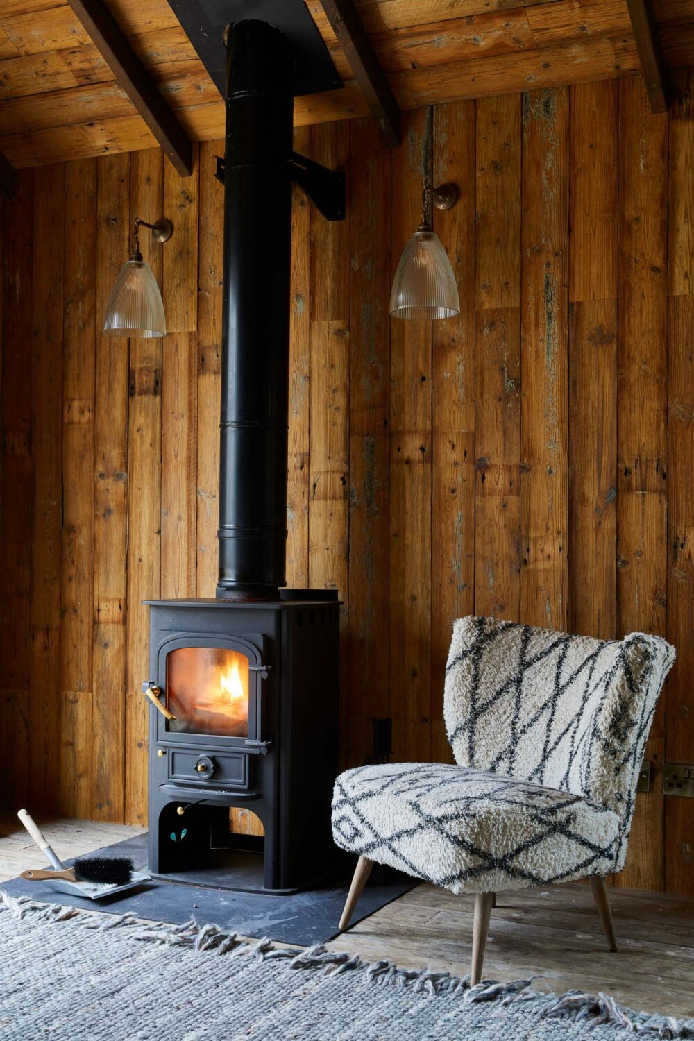 wooden cabin with a fireplace and boucle chair