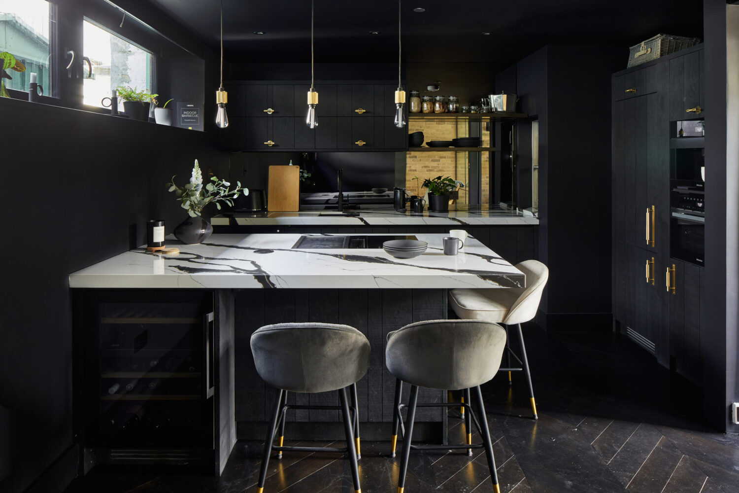 kitchen with dark black cabinets with an island housing a wine cooler and cooktop