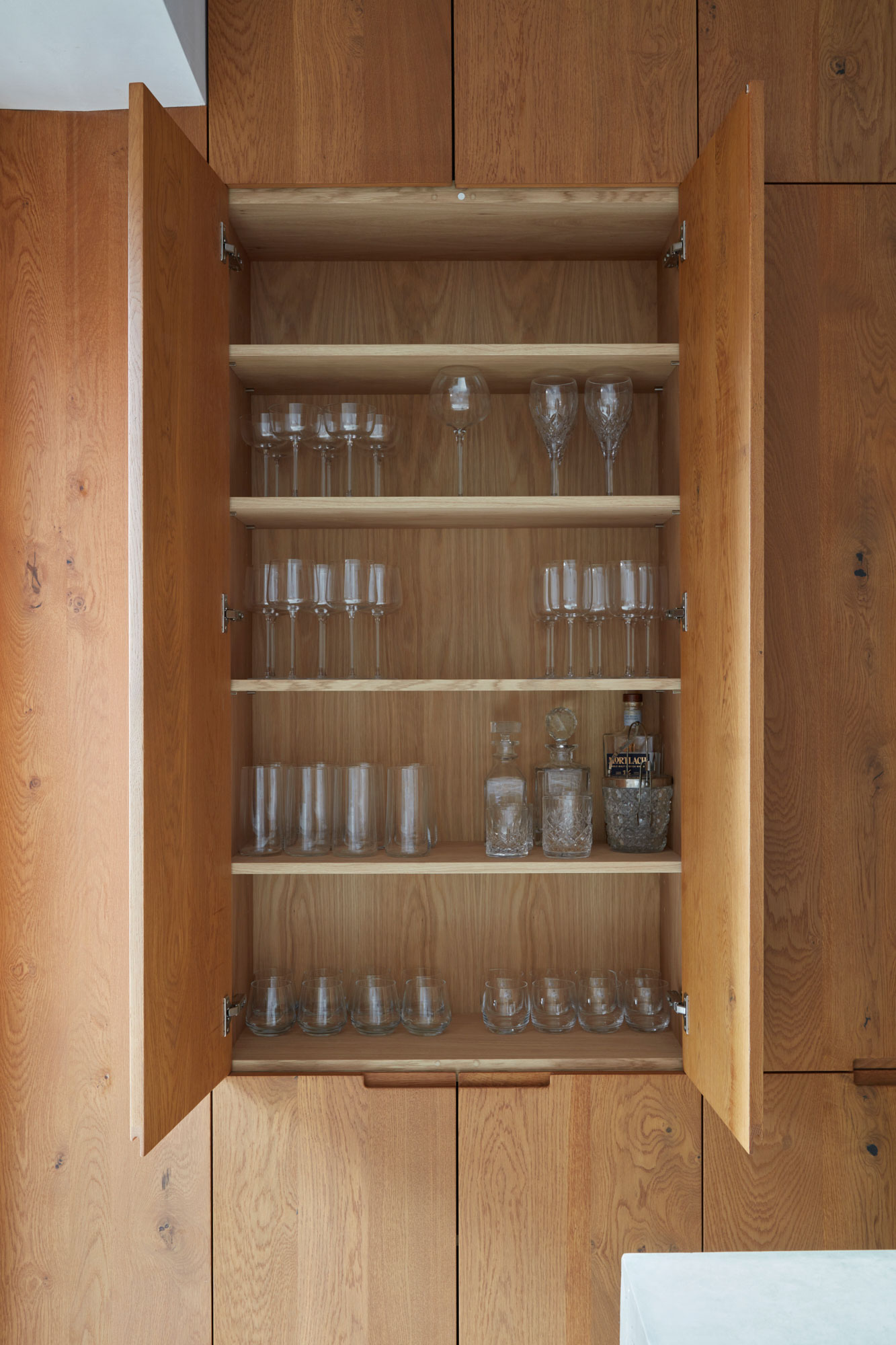 Glass storage inside tall oak kitchen cabinets